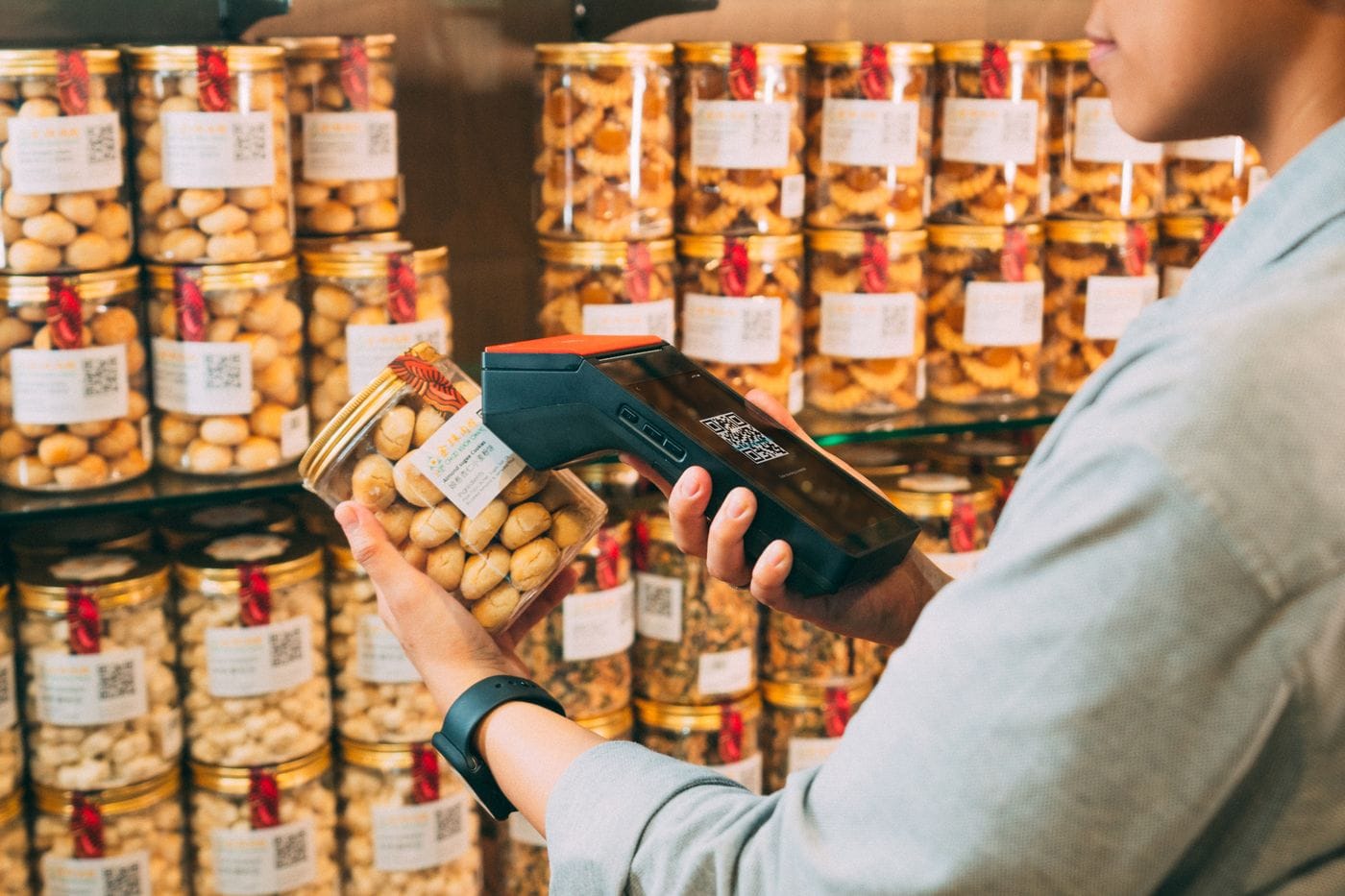 A store employee scans a product's barcode with a handheld scanner to look up stock and pricing.